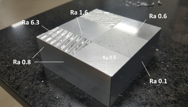 Surface finish comparison block showing rough and fine machining textures.